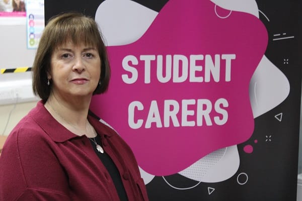 Marie Jameson in front of banner with words Student Carers.